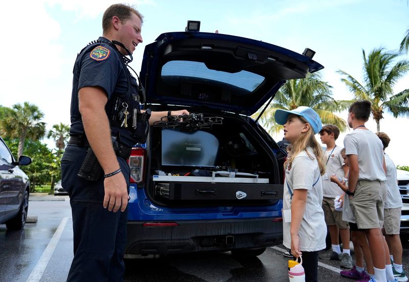Officer Cory Metelsky answers questions from Charlie Neville, 8, about a police drone at the Palm Beach Marina on June 10, 2025, during a Safeguard Palm Beach Youth Academy program.