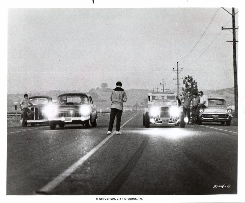 In a scene from "American Graffiti," Terry (Charlie Martin Smith, center) gives the starting signal for a race between Big John Milner (Paul Le Mat) in his '32 custom Ford deuce coupe, and Bob Falfa (Harrison Ford) a drag-racing champion from a nearby town.
