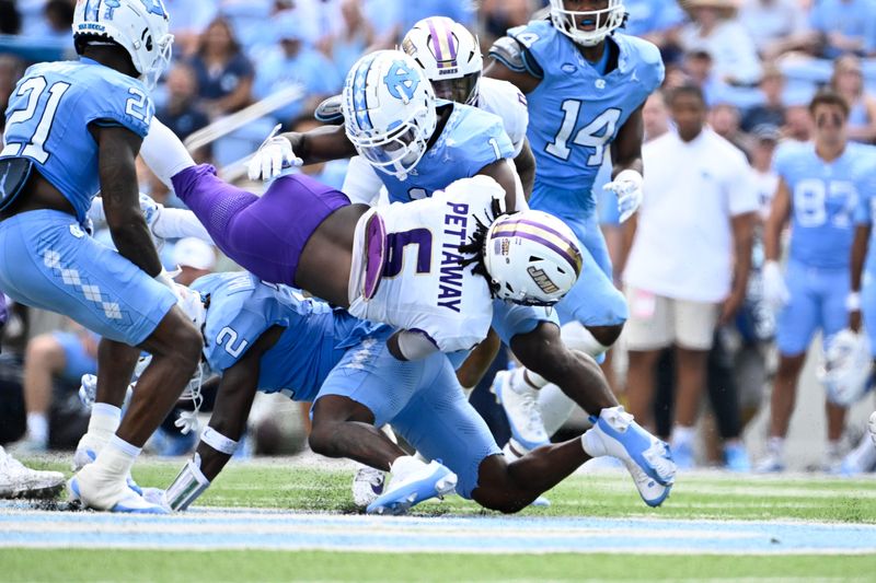 Sep 21, 2024; Chapel Hill, North Carolina, USA; James Madison Dukes running back George Pettaway (6) is tackled by North Carolina Tar Heels defensive backs Kaleb Cost (21) and Jakeen Harris (2) and Antavious Lane (1) in the second quarter at Kenan Memorial Stadium. Mandatory Credit: Bob Donnan-Imagn Images