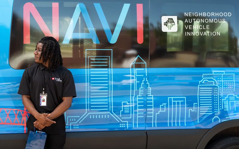 JTA intern Isaiah Alfred leans against one of the NAVI vehicles after the Jacksonville Transportation Authority held a ribbon-cutting ceremony for the Neighborhood Autonomous Vehicle Innovation at VyStar Ballpark Friday June 27, 2025. [Doug Engle/Florida Times-Union]