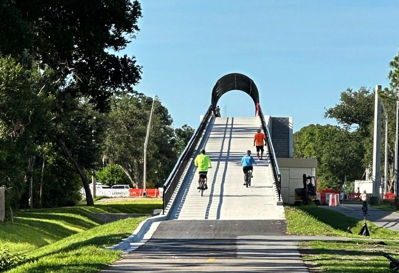 Southbound cyclists navigate the incline of the new Legacy Trail overpass bridge at Bee Ridge Road. The overpass opened for pedestrians and cyclists on June 17, 2025. Staircases on both sides of the bridge are still under construction. The Florida Department of Transportation said the overpass at Clark Road will open on July 2.