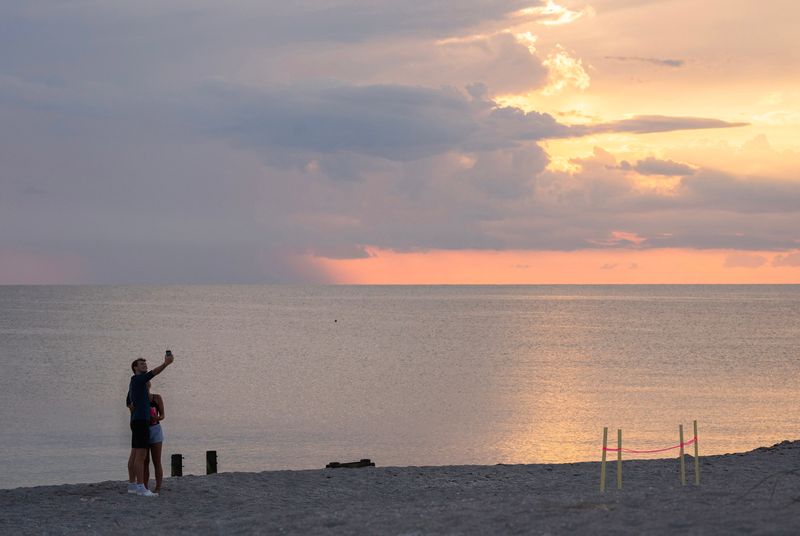 Beachgoers take a sunset selfie June 24, 2025, on North Brohard Beach near a turtle nest in roughly the same area fireworks for the July 4 display in Venice will be staged.