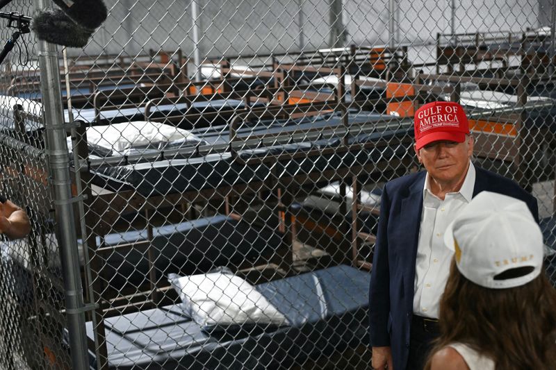 US President President Donald Trump speak with Secretary of Homeland Security Kristi Noem as they tour a migrant detention center, dubbed "Alligator Alcatraz," located at the site of the Dade-Collier Training and Transition Airport in Ochopee, Florida on July 1, 2025.