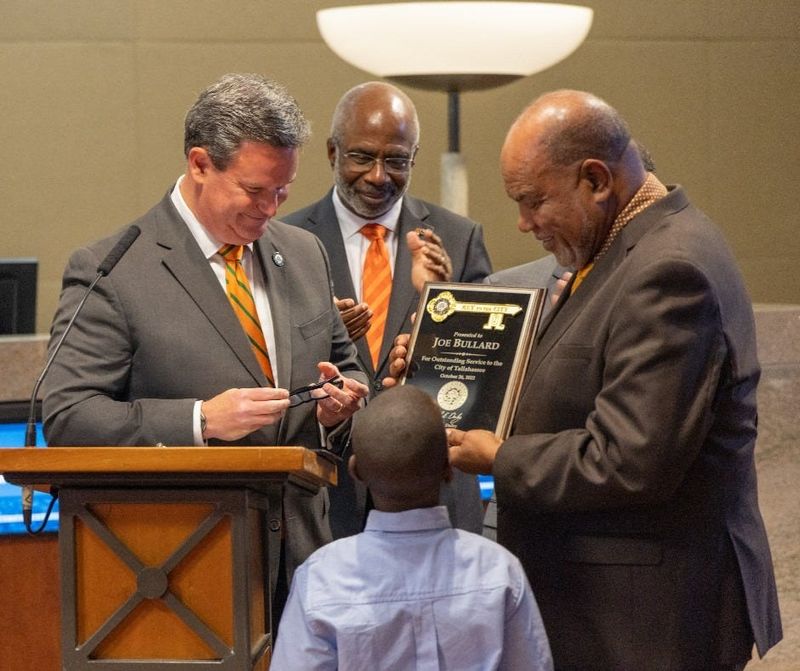 Radio host Joe Bullard receives the key to the city from Mayor John Dailey as then Florida A&M University President Larry Robinson looks on.