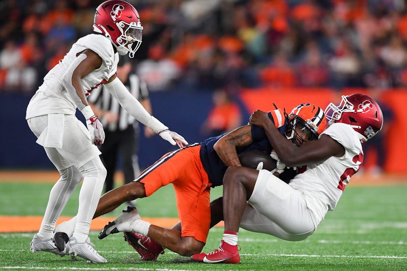 Sep 20, 2024; Syracuse, New York, USA; Stanford Cardinal linebacker David Bailey (right) tackles Syracuse Orange wide receiver Umari Hatcher (5) as cornerback Collin Wright (6) looks on during the second half at the JMA Wireless Dome. Mandatory Credit: Rich Barnes-Imagn Images