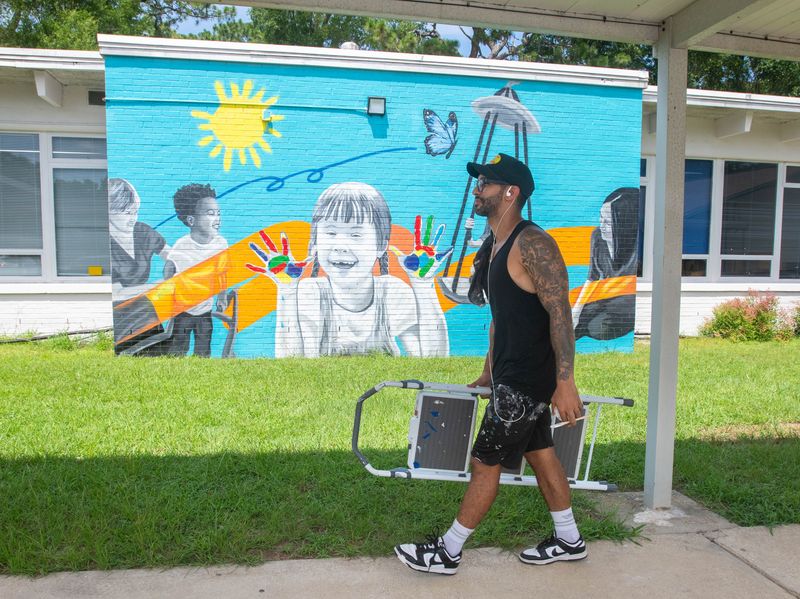 Artist Daniel Andreu walks past one of several murals that he is creating at the Arc Gateway in Pensacola on July 2, 2025.