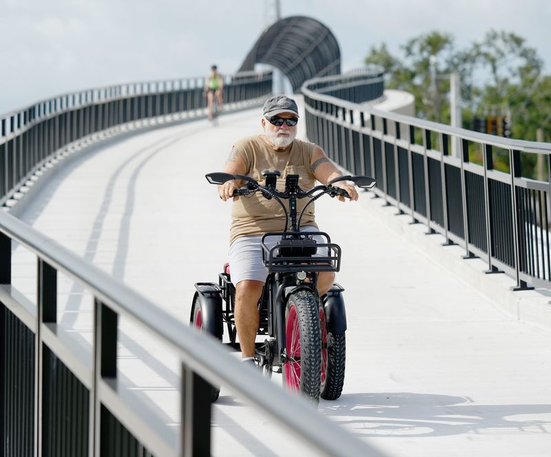 An e-biker travels on the Legacy Trail overpass bridge over Clark Road in Sarasota on July 2, 2025.