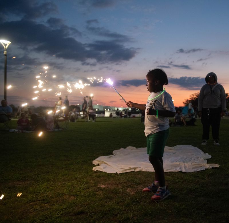 Zaire Walker, 5, from Baltimore, entertains himself while waiting for the fireworks to start at Community Maritime Park in downtown Pensacola on July 4, 2025.