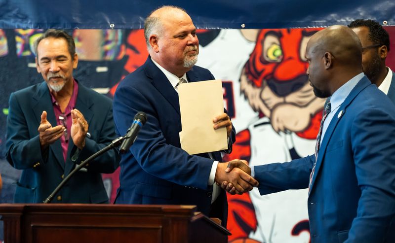 Duval County Public Schools Superintendent Christopher Bernier, left, shakes hands with Principal Truitte Moreland of Andrew Jackson High School after announcing that his school went from a "C" to an "A" on the state-issued school grades, Tuesday July 8, 2025. Teachers and administrators from 10 schools, as well as some students and families, talked about steps their schools took to improve on the state grades at Andrew Jackson High School in Jacksonville, Fla. Tuesday. [Doug Engle/Florida Times-Union]