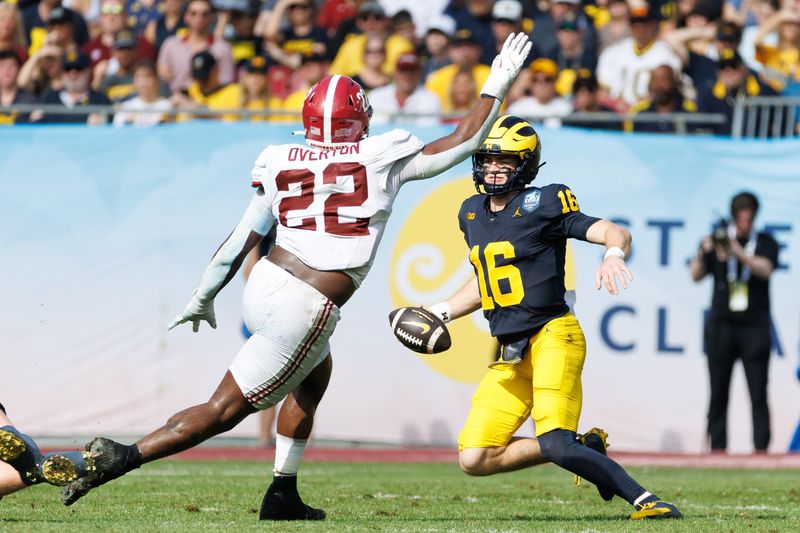 Dec 31, 2024; Tampa, FL, USA; Michigan Wolverines quarterback Davis Warren (16) jukes Alabama Crimson Tide defensive lineman LT Overton (22) during the first half at Raymond James Stadium. Mandatory Credit: Matt Pendleton-Imagn Images