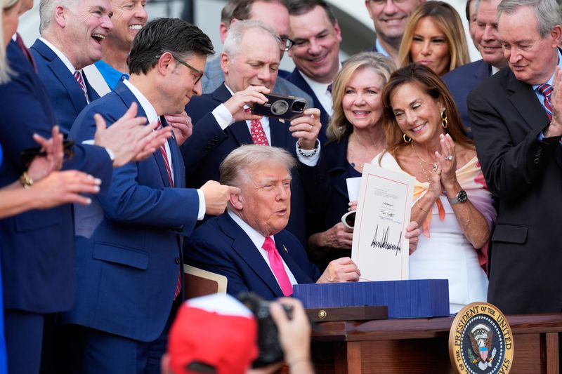 WASHINGTON, DC - JULY 04: President Donald Trump holds up the "One, Big Beautiful Bill" Act that was signed into law during an Independence Day military family picnic on the South Lawn of the White House. (Photo by Alex Brandon - Pool/Getty Images)