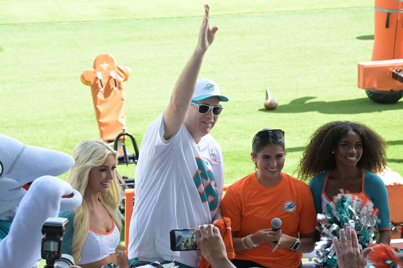 Miami Dolphins fan Ian 'Big E' Berger waves to the training camp crowd after being recognized as "Orange Jersey Fan of the Day" by the team on July 26, 2025.