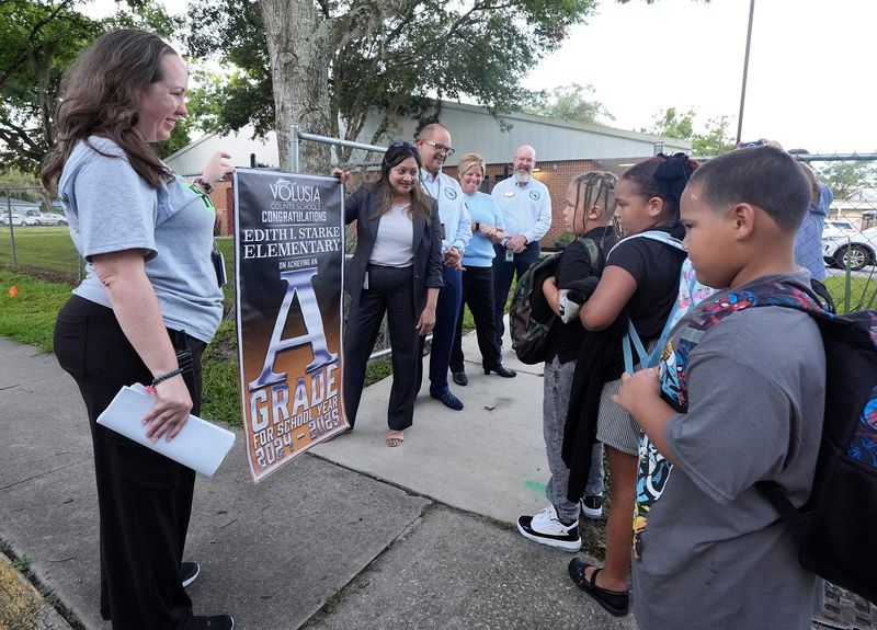 Volusia County Superintendent Carmen Balgobin awards Edith I Starke principal Jessica Aivazis with an "A" grade banner on the first day of school in DeLand, Monday, August 11, 2025.