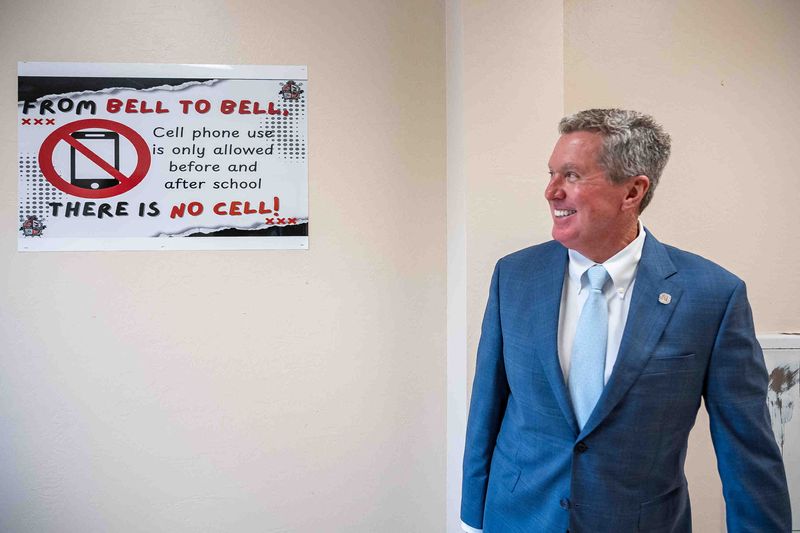 Palm Beach County schools Superintendent Mike Burke does a double take on new signage at Tradewinds Middle School on the first day of the new school year in Greenacres on Aug, 11. The policy limits cellphone use during the school day.