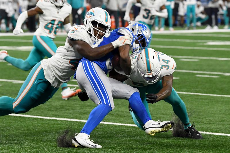 Aug 16, 2025; Detroit, Michigan, USA; Detroit Lions running back Deon Jackson (36) gets tackled by Miami Dolphins linebacker Channing Tindall (41) and safety Jordan Colbert (34) in the third quarter at Ford Field. Mandatory Credit: Eamon Horwedel-Imagn Images