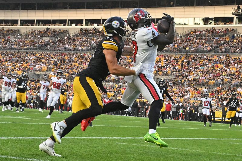 Aug 16, 2025; Pittsburgh, Pennsylvania, USA; Tampa Bay Buccaneers running back Bucky Irving (7) catches a touchdown pass in front of Pittsburgh Steelers linebacker Payton Wilson (41) during the first quarter at Acrisure Stadium. Mandatory Credit: Barry Reeger-Imagn Images