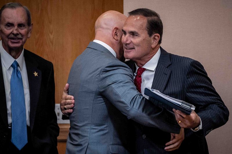 Palm Beach County county administrator Joseph Abruzzo, left, greets county clerk Mike Caruso, right, at a county commission meeting at the Robert Weisman Palm Beach County Governmental Center in downtown West Palm Beach, Fla., on August 19, 2025. THOMAS CORDY/PALM BEACH POST