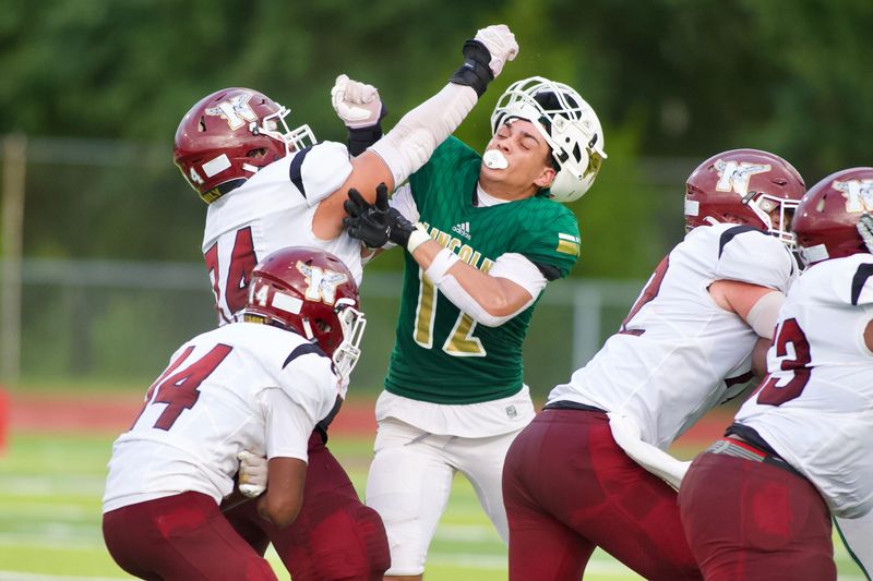 Lincoln football's Jackson Mitchell (#12) fights through contact as the Trojans beat Niceville 36-29 on Friday Aug. 22, 2025 at Chiles High School