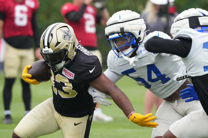 Aug 14, 2025; Carson, CA, USA; New Orleans Saints running back Clyde Edwards-Helaire (23) carries the ball against Los Angeles Rams linebacker Chris Paul Jr. (54) and cornerback Cam Lampkin (33) during a joint practice at the Dignity Health Sports Park. Mandatory Credit: Kirby Lee-Imagn Images