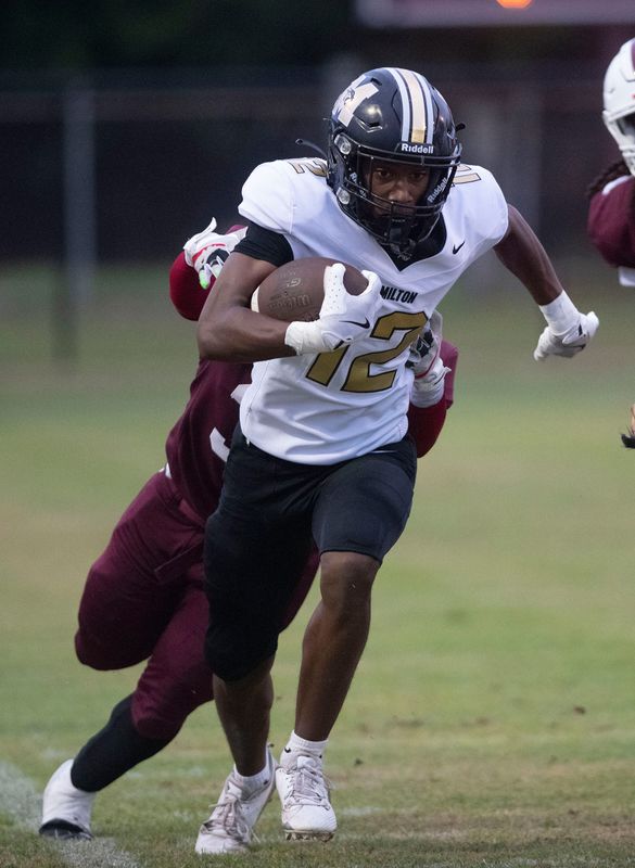 Milton's RJ Coleman (No. 12) works to stay inbound on the near sideline while dragging a Pensacola High School defender during Friday night's football matchup against the Panthers and the Tigers.