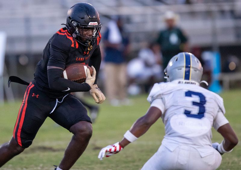 Lake Wales' Kaneilius Purdy (2) looks for running room as RIdge Community's Daniel James (3) closes in on Friday night at Legion Field.
