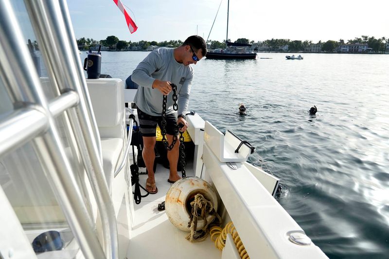 Palm Beach police officer Anthony DeJesse loads a buoy onto the Palm Beach Police marine unit while divers remove illegal moorings and bottom gear north of the Flagler Bridge near Palm Beach in the Intracoastal Waterway on Aug. 26, 2025.