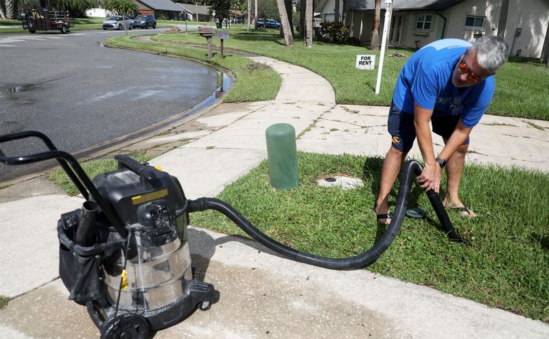 Kevin Stevenson, a resident of Sleepy Hollow in Port Orange, uses a shop vac to help reduce flooding near his home on Tuesday. Weekend rains brough floodwaters into his home.