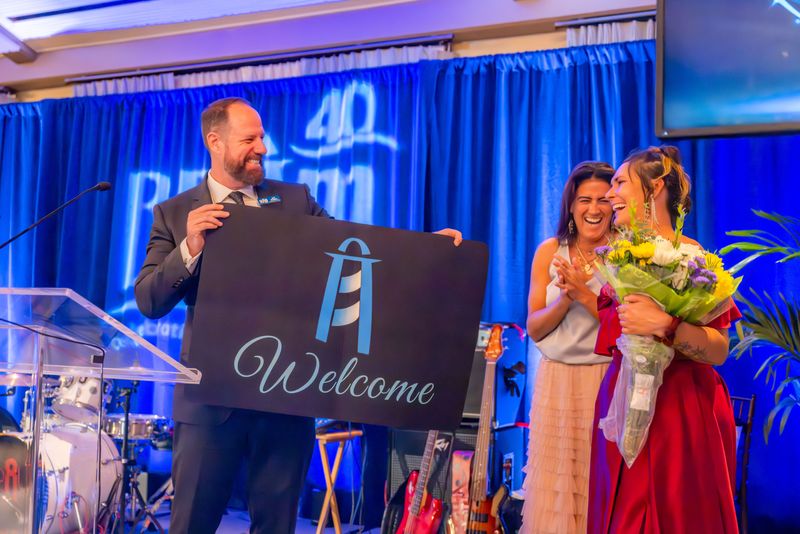 At BEAM's recent 40th anniversary gala, CEO Jeff Winkler, left, celebrates a client named Brittany, right front, who became a first-time homeowner with the help of the nonprofit's Single Parent Program.