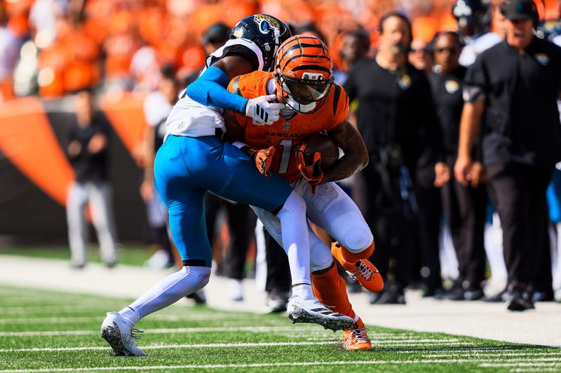 Sep 14, 2025; Cincinnati, Ohio, USA; Cincinnati Bengals wide receiver Ja'Marr Chase (1) runs with the ball against Jacksonville Jaguars defensive back Travis Hunter (12) in the second half at Paycor Stadium. Mandatory Credit: Katie Stratman-Imagn Images