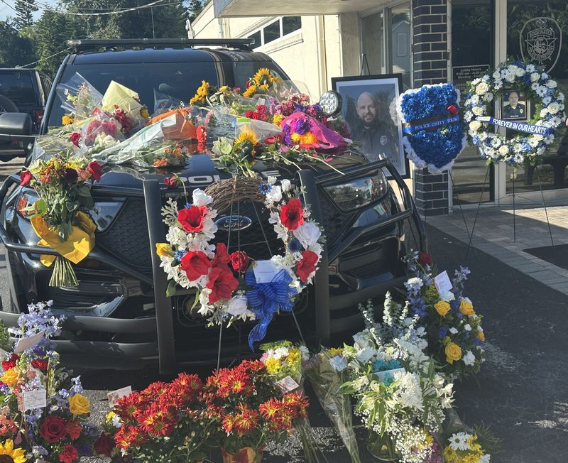 The patrol car of Edgewater Police Officer David Jewell is covered with flowers in front of the police station at Riverside Drive and Park Avenue, Tuesday, Sept. 16, 2025. Jewell was off duty when he was shot and killed at an Ormond-by-the-Sea Circle K Monday, Sept. 15.