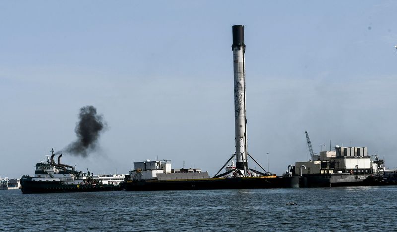Spectators watch as a SpaceX first-stage booster that launched a GPS III satellite is brought into Port Canaveral on July 4, 2020, aboard the drone ship Just Read the Instructions.