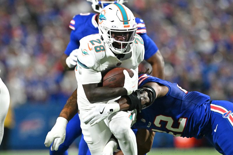 Sep 18, 2025; Orchard Park, New York, USA; Miami Dolphins running back de'von Achane (28) runs against Buffalo Bills linebacker Dorian Williams (42) in the first quarter at Highmark Stadium. Mandatory Credit: Mark Konezny-Imagn Images