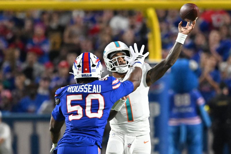 Sep 18, 2025; Orchard Park, New York, USA; Miami Dolphins quarterback Tua Tagovailoa (1) passes against Buffalo Bills defensive end Greg Rousseau (50) in the second quarter at Highmark Stadium. Mandatory Credit: Mark Konezny-Imagn Images