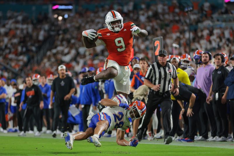 Sep 20, 2025; Miami Gardens, Florida, USA; Miami Hurricanes tight end Elija Lofton (9) hurdles over Florida Gators defensive back Devin Moore (28) during the second quarter at Hard Rock Stadium. Mandatory Credit: Sam Navarro-Imagn Images