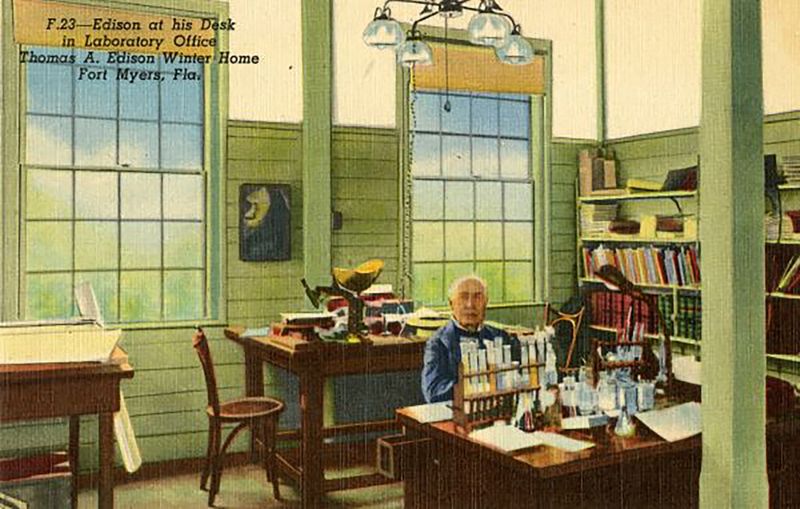 Edison at his desk in laboratory office in Fort Myers. From the Postcard collection. Accompanying note: “Pausing from his rubber experiments, Edison looks up from his laboratory desk. On it can be seen test tubes, Erienmeyer flasks, beakers and other equipment used in his goldenrod research.”