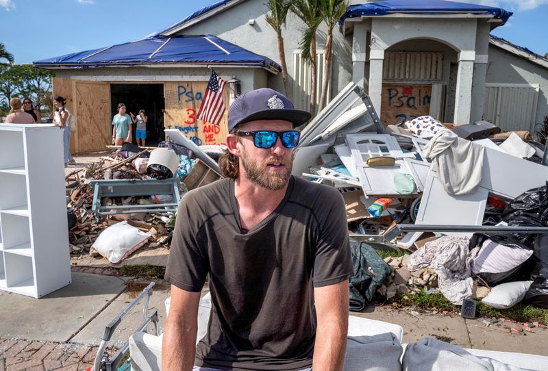 Carter McMasters sits in front of his damaged home on October 14, 2024 in Wellington, Florida. Their home was hit by a tornado spawned from Hurricane Milton last week.