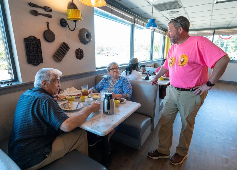 From right, owner Chris Titze chats with regular customers Clara and Butch Oxendine at the remodeled Village Inn restaurant in Pace on Oct. 1, 2025.