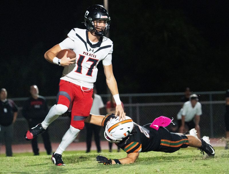 Logan Flaherty, the quarterback of Port Charlotte eludes a Dunbar defender during a game at Dunbar on Friday, Oct. 10, 2025. Port Charlotte won.