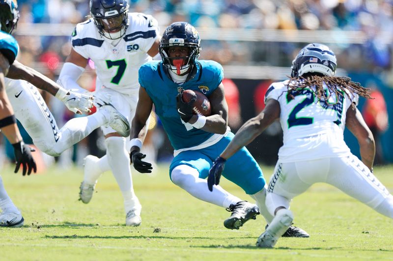 Jacksonville Jaguars running back Travis Etienne (1) rushes for yards against Seattle Seahawks cornerback Shaquill Griffin (24) and linebacker Uchenna Nwosu (7) during the second quarter of an NFL football matchup, Sunday, Oct. 12, 2025, at EverBank Stadium in Jacksonville, Fla. The Seahawks defeated the Jaguars 20-12.