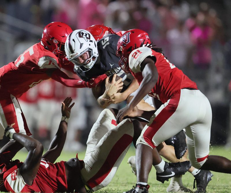 Palm Beach Central cornerback Semajay Robinson (5) gets stopped by Vanguard defensive back Roger Stevens (15) and Vanguard Kemohn Pinkney (21) during an FHSAA football game at Booster Stadium in Ocala, FL on Friday, October 17, 2025. [Alan Youngblood/Ocala Star-Banner]