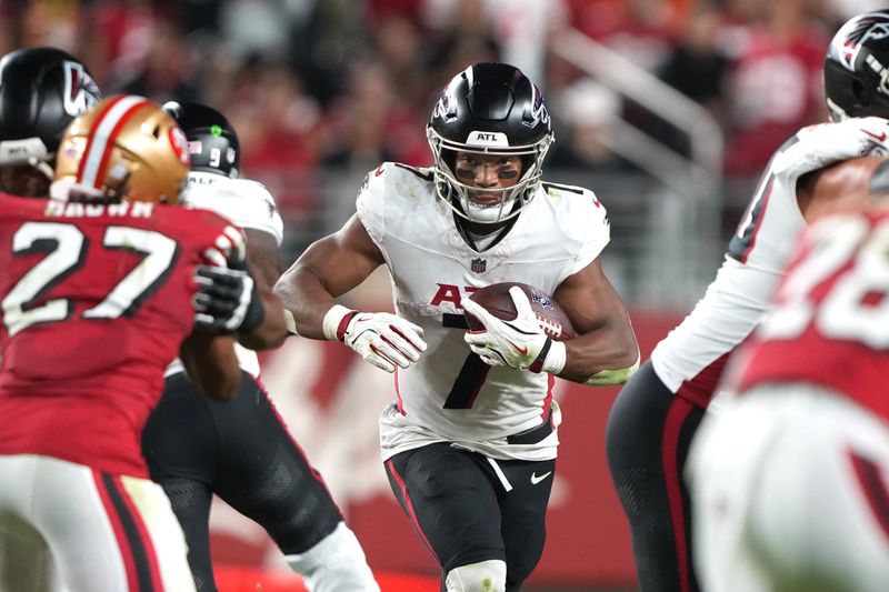 Oct 19, 2025; Santa Clara, California, USA; Atlanta Falcons running back Bijan Robinson (center) carries the ball against San Francisco 49ers safety Ji'Ayir Brown (27) during the third quarter at Levi's Stadium. Mandatory Credit: Darren Yamashita-Imagn Images