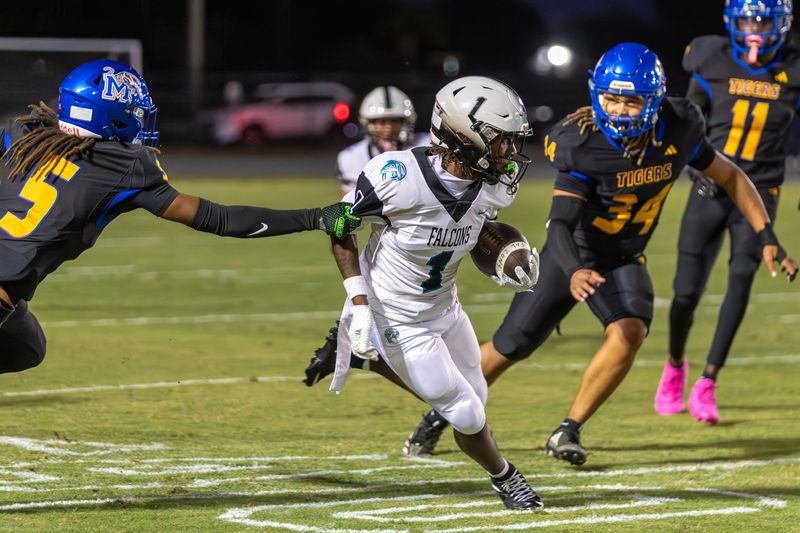 Jensen Beach’s Sylvester Brinkley (1) runs the ball up the field as Martin County’s Jeromie King (5) and Tyrone Robinson (34) close in during a high school football game against Martin County on Oct. 30, 2025, at Martin County High School. Martin County won 7-3.