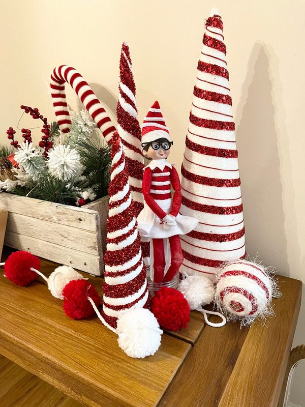A Waldo-esque elf tries to blend into a candy-striped display.