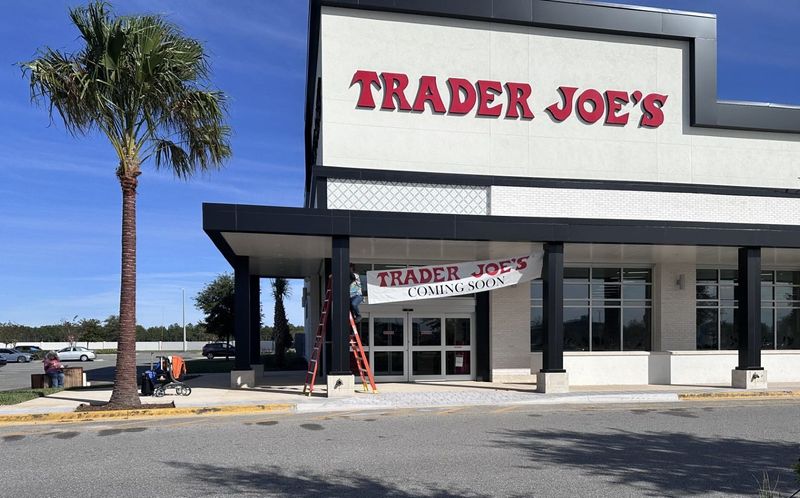 A worker at Trader Joe's hangs a "coming soon" banner on arches outside the new store at 1511 Cornerstone Boulevard in Daytona Beach on Nov. 10, 2025. The store is scheduled to open on Nov. 14, 2025, according to the Trader Joe's website.
