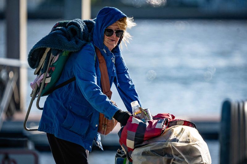 Pam Lamb, Lake Worth Beach, walks the sidewalk between Snook Islands Natural Area and Bryant Park near the Lake Worth Sailing Club Docks after an overnight cold front moved through Lake Worth Beach, Fla., on November 11, 2025. "I am cold," she said.