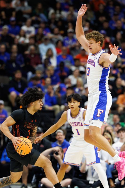 Nov 16, 2025; Jacksonville, Florida, USA; Miami Hurricanes guard Tre Donaldson (3) looks to pass while Florida Gators center Micah Handlogten (3) jumps to defend during the first half at VyStar Veterans Memorial Arena. Mandatory Credit: Matt Pendleton-Imagn Images