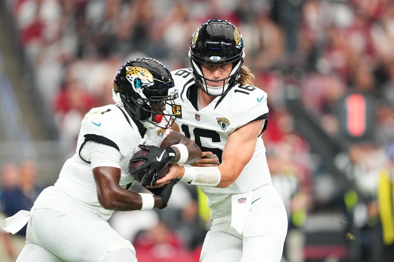 Nov 23, 2025; Glendale, Arizona, USA; Jacksonville Jaguars quarterback Trevor Lawrence (16) hands the ball off to Jacksonville Jaguars running back Travis Etienne Jr. (1) during the first quarter against the Arizona Cardinals at State Farm Stadium. Mandatory Credit: Joe Camporeale-Imagn Images