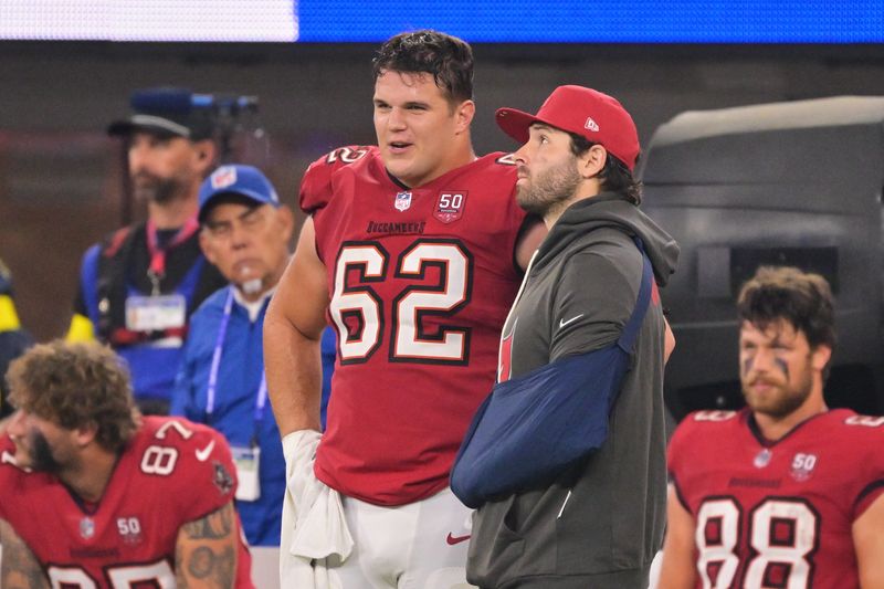 Nov 23, 2025; Inglewood, California, USA; Tampa Bay Buccaneers quarterback Baker Mayfield (6) stands on the sideline with his left arm in a sling and chats with center Graham Barton (62) during the fourth quarter at SoFi Stadium. Mandatory Credit: Jayne Kamin-Oncea-Imagn Images