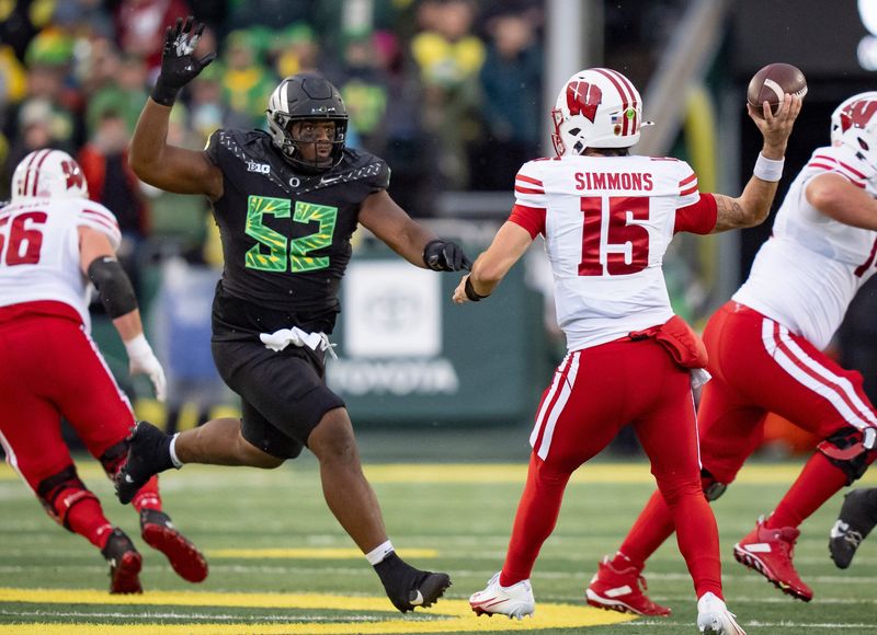 Oregon defensive lineman A'Mauri Washington, left, pressures Wisconsin quarterback Hunter Simmons as the Oregon Ducks host the Wisconsin Badgers on Oct. 25, 2025, at Autzen Stadium in Eugene, Oregon.