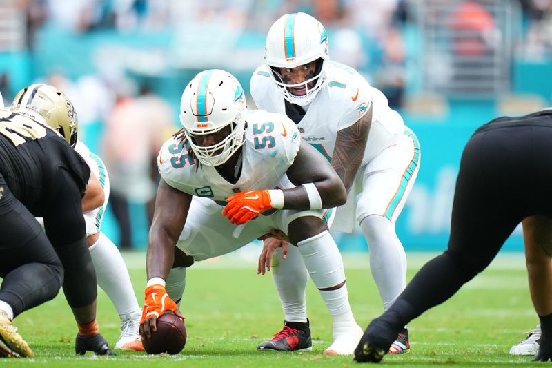 Nov 30, 2025; Miami Gardens, Florida, USA; Miami Dolphins quarterback Tua Tagovailoa (1) under center Aaron Brewer (55) against the New Orleans Saints during the first half at Hard Rock Stadium. Mandatory Credit: Rich Storry-Imagn Images